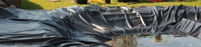 ein flacher Teich mit schwarzer Folie ausgekleidet